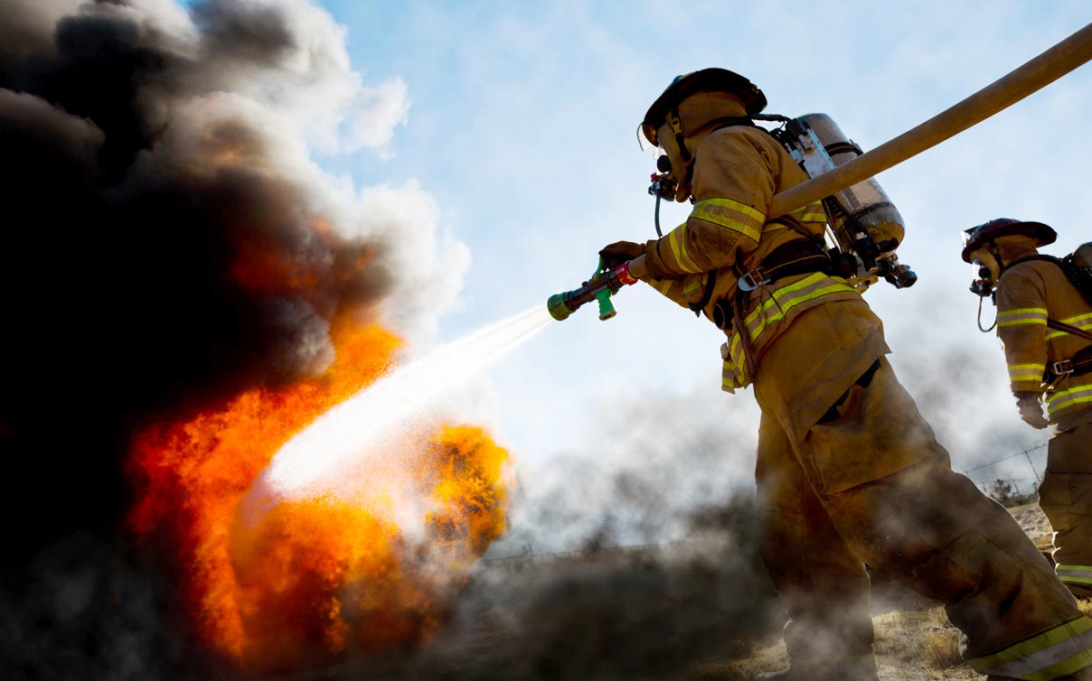 Close up of firefighters battling wildfire with water