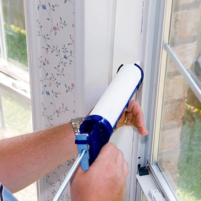 Man weatherizing and sealing house windows