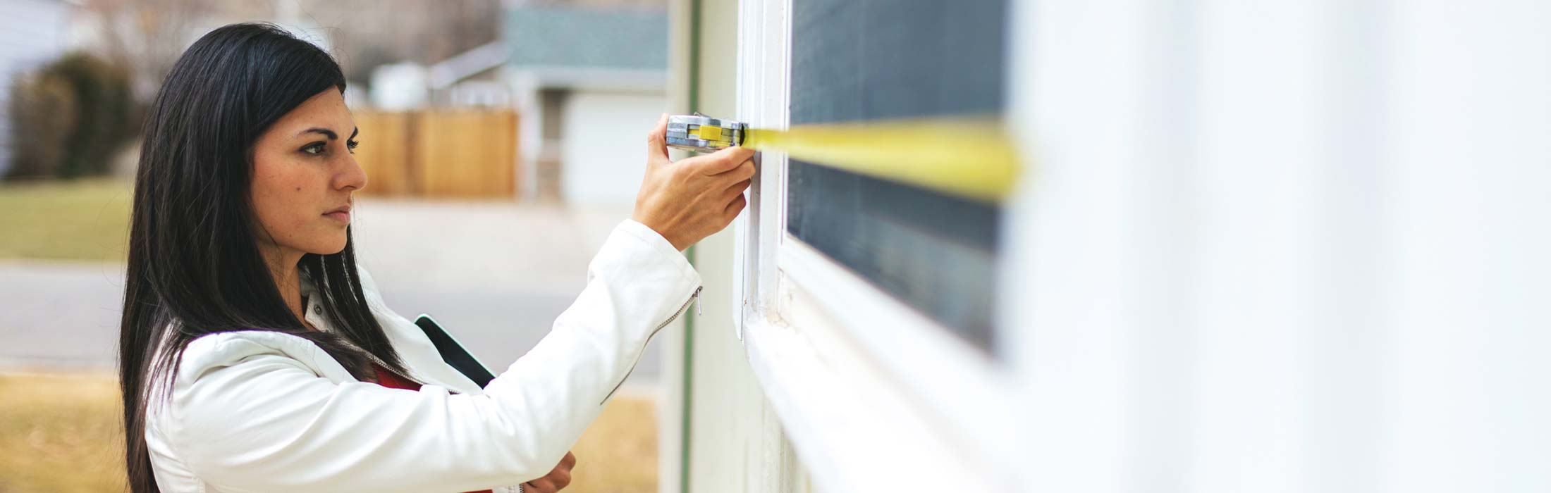 Professional female contractor taking window measurements
